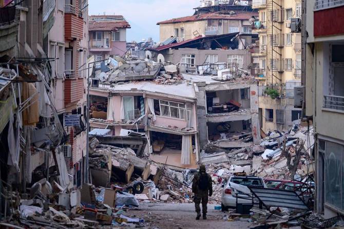 A Turkish soldier walks among destroyed buildings in Hatay