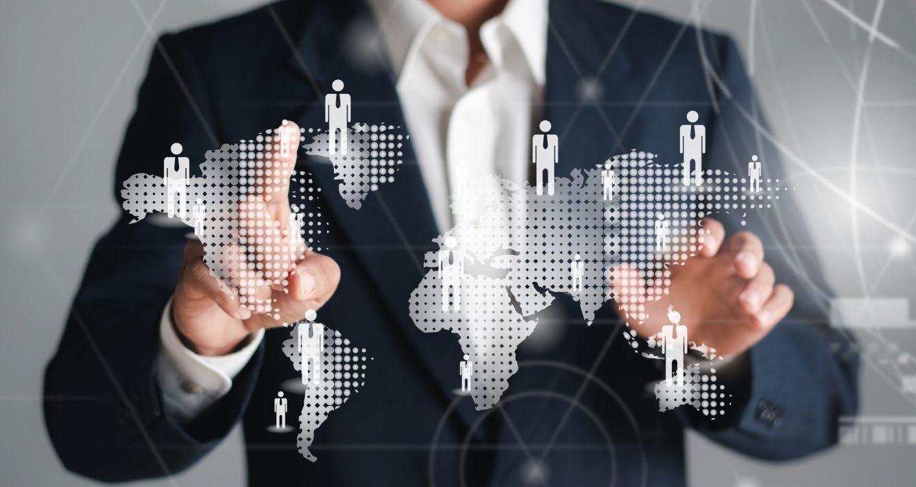 A person in a suit points to an illustration of the globe with people scattered throughout.