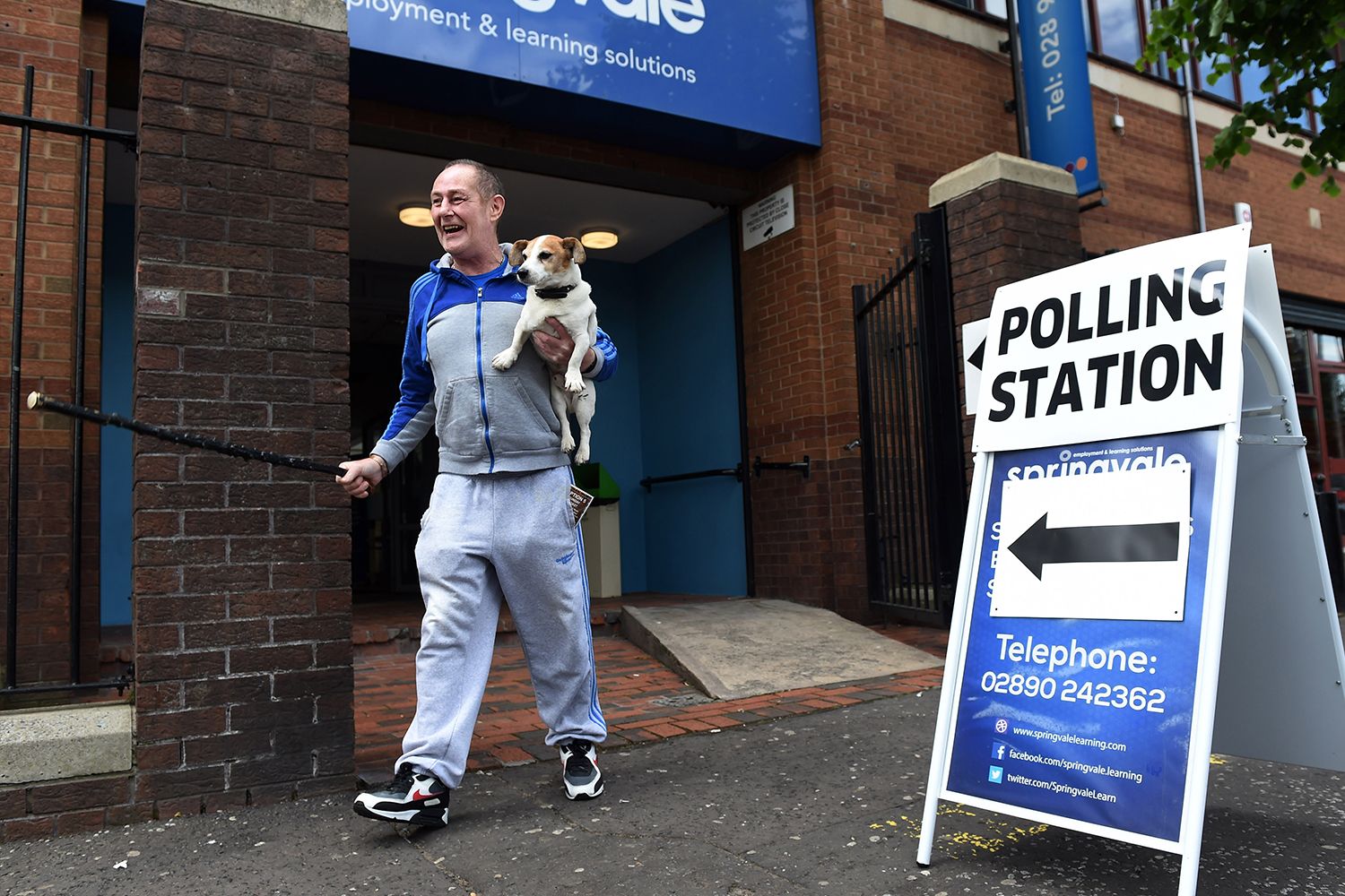 A man accompanied by his dog laughs as he exits a polling station after voting in the EU referendum.