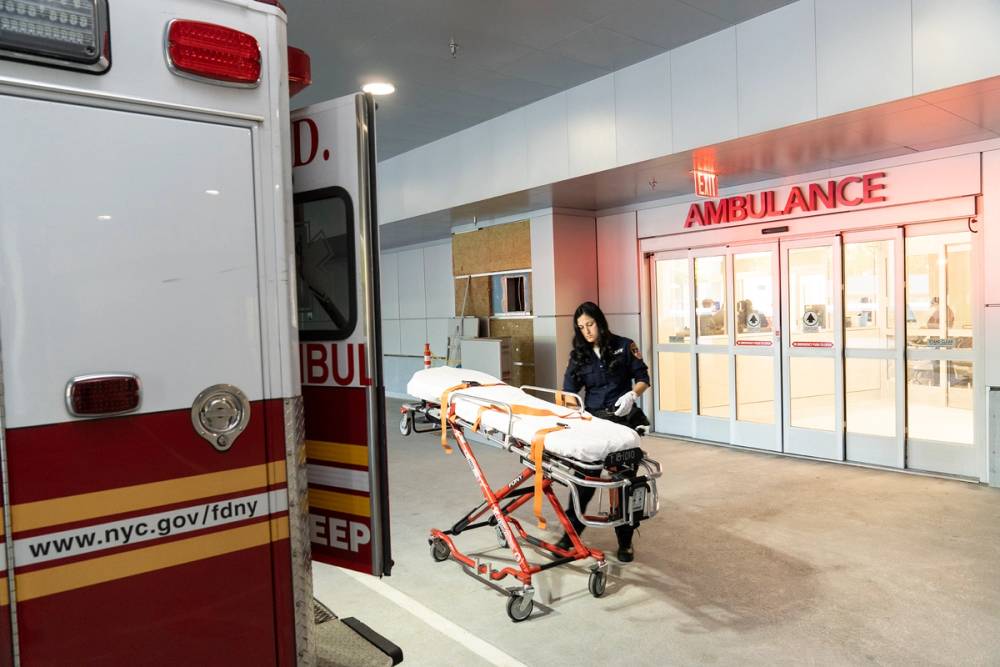 A female EMT holds a gurney outside the emergency room.