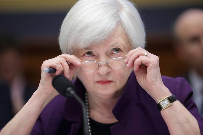 Federal Reserve Chair Janet Yellen testifies before the House Finance Committee in the Rayburn House Office Building November 4, 2015. She is wearing a purple blazer and in the act of removing her glasses from her face.