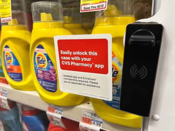 A sign in a CVS describes how to unlock the locked display case using the CVS app. 