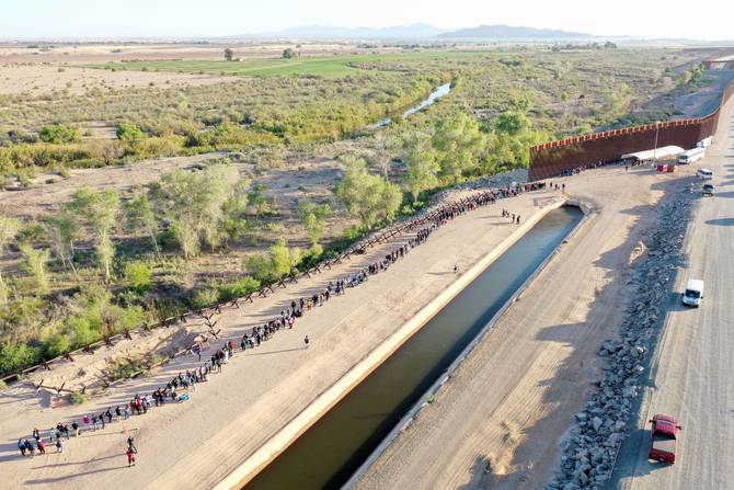 In an aerial view, immigrants seeking asylum in the United States wait in line near the border fence to be processed by U.S. Border Patrol agents