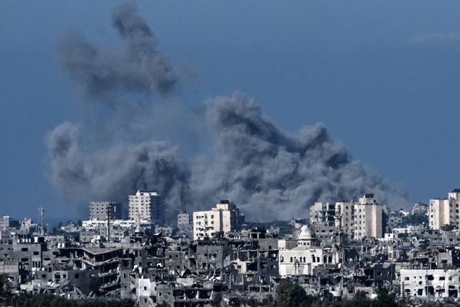 A picture taken from the Israeli side of the border with the Gaza Strip shows smoke rising behind destroyed buildings in the norther-western part of the Palestinian enclave during an Israeli bombing on October 21, 2023