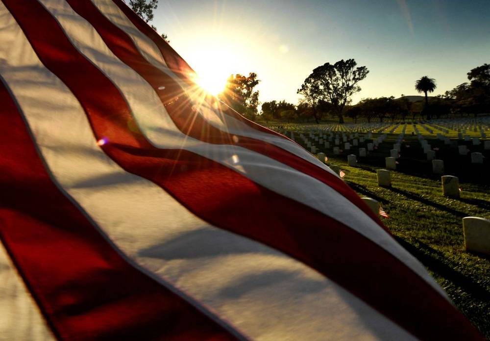 The sun sets over a flag at the Los Angeles National Military Cemetery two days before Memorial Day in Los Angeles, California on May 26, 2018.