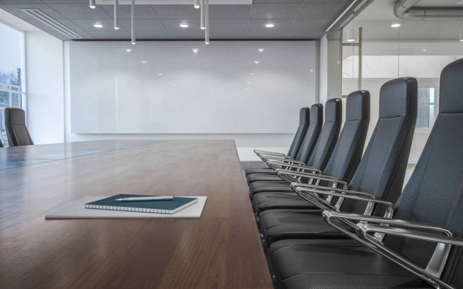 A row of chairs lined up next to a table in an empty board room
