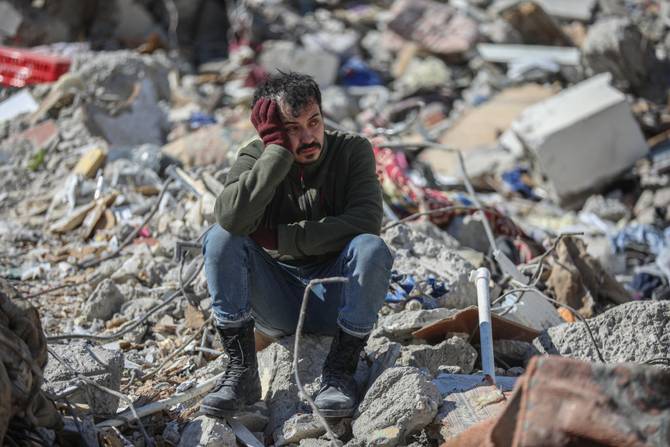 A man sits amongst the rubble of collapsed buildings on February 9, 2023 in Kahramanmaras, Turkey