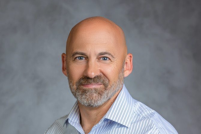 A bald man with a beard smiles at the camera.