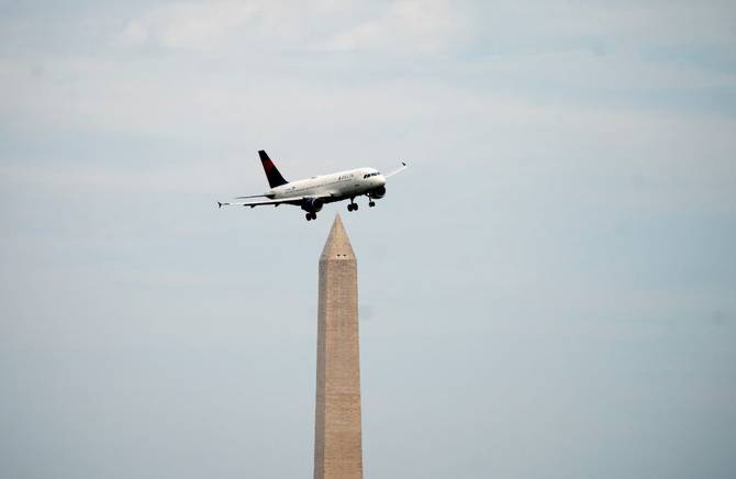 A plane flies over the Washington Memorial