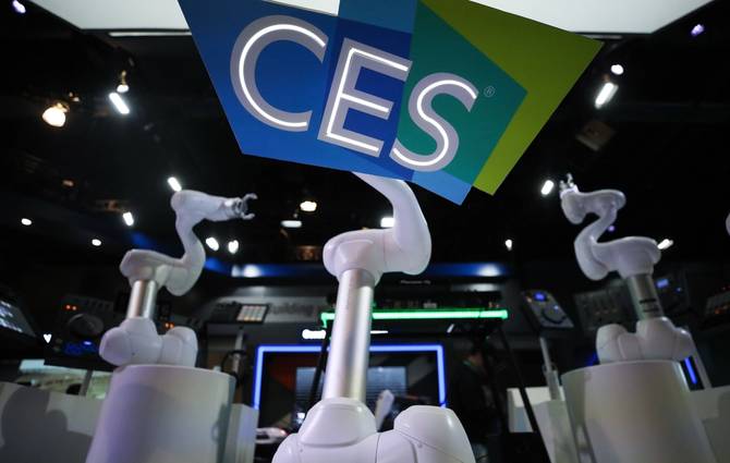 Image from inside a CES showroom, with robotic arms in foreground and CES banner in the background. 