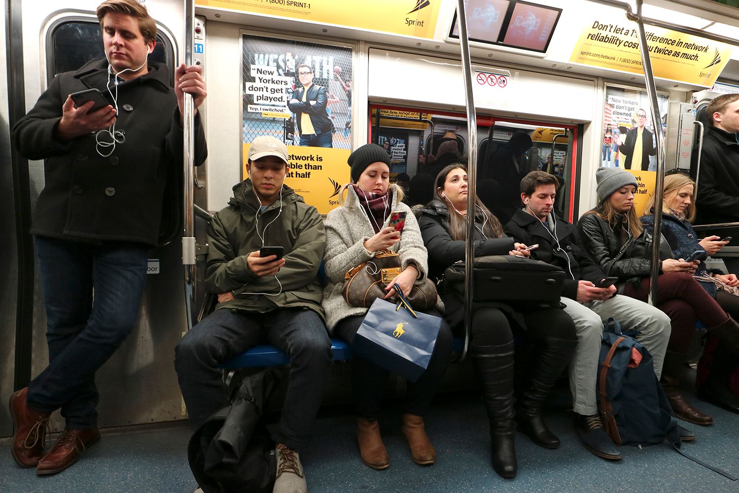 Commuters use their mobile phones while riding on a train.