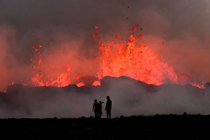 People watch flowing lava during an volcanic eruption near Litli Hrutur, south-west of Reykjavik in Iceland on July 10, 2023. A volcanic eruption started on July 10, 2023 around 30 kilometres (19 miles) from Iceland's capital Reykjavik, the country's meteorological office said, marking the third time in two years that lava has gushed out in the area.