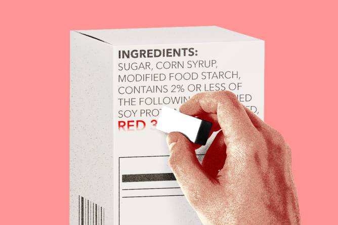 Hand erasing "Red 3" on ingredient label