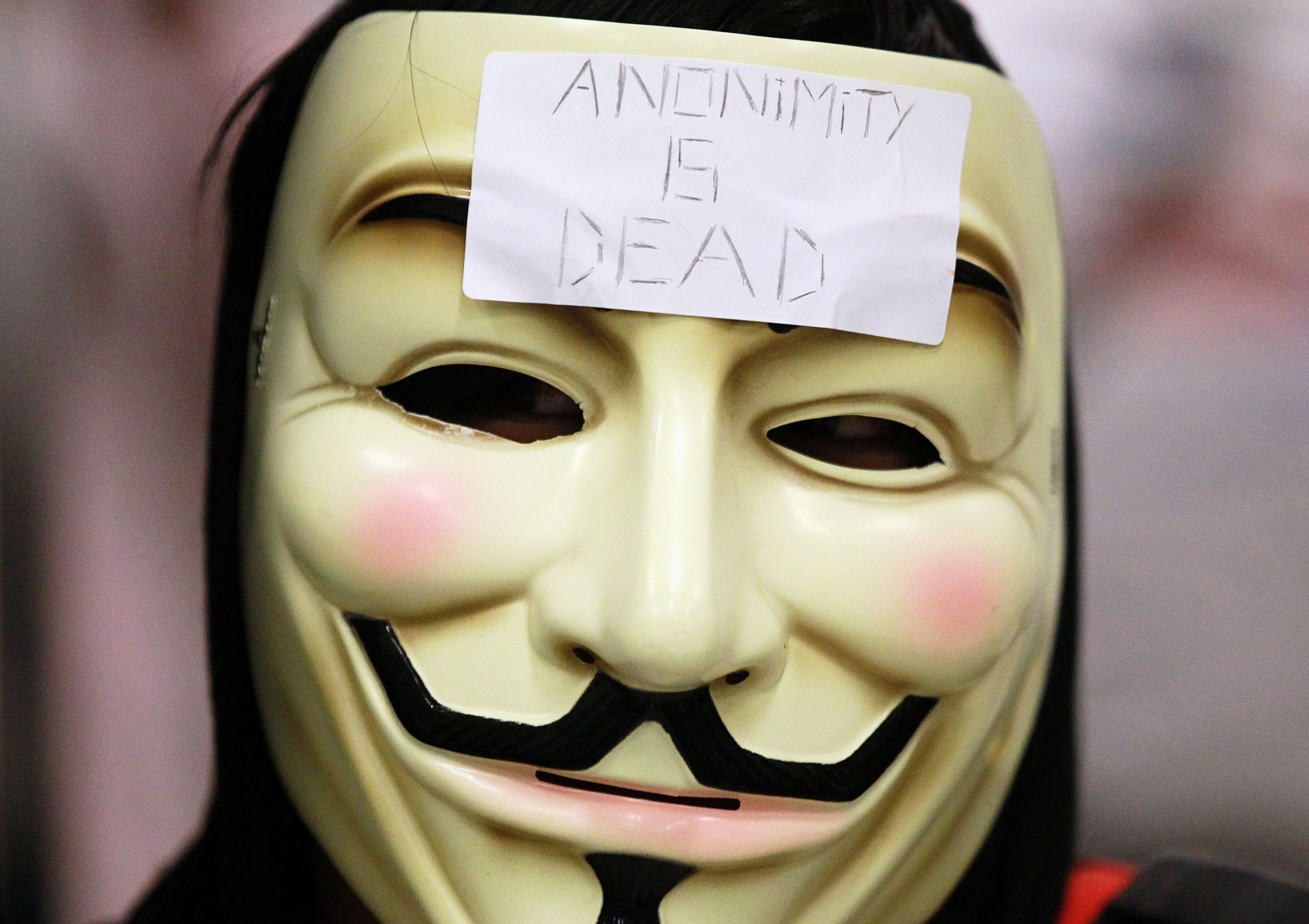 Close crop of v for vendetta mask, white plastic, black mustache and eyebrows, eye and mouth holes, sculpted cheekbones.