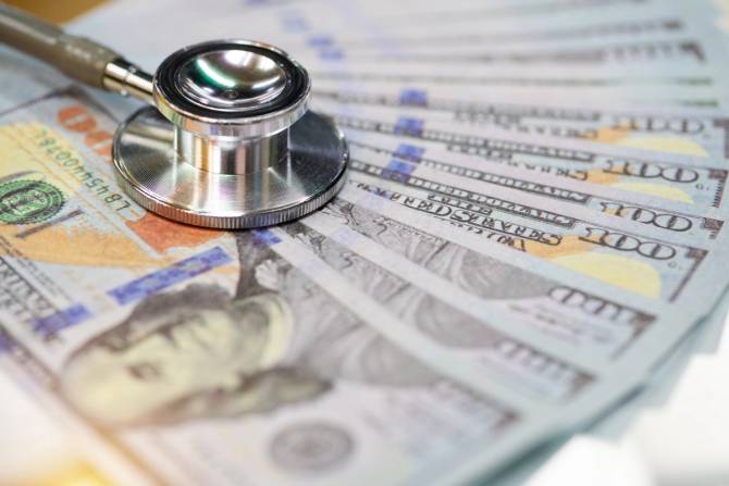 A stethoscope on a pile of money.