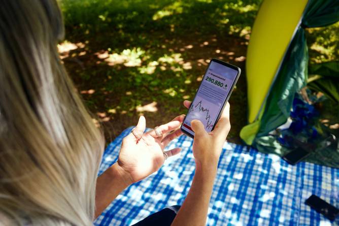 A woman watches a stock on her phone
