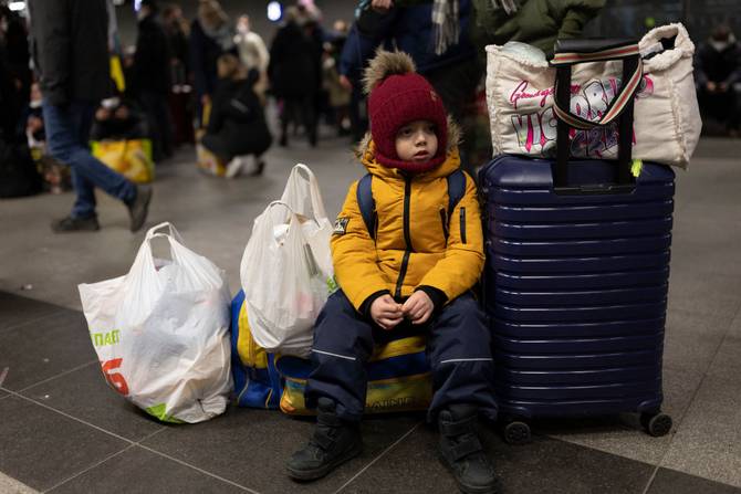 A Ukrainian refugee boy waits with luggage