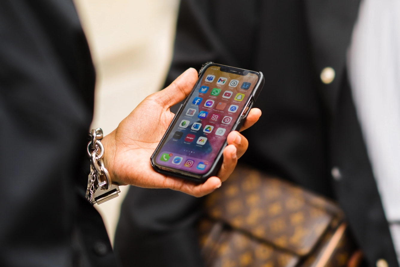 User holds iPhone that displays workplace app icons