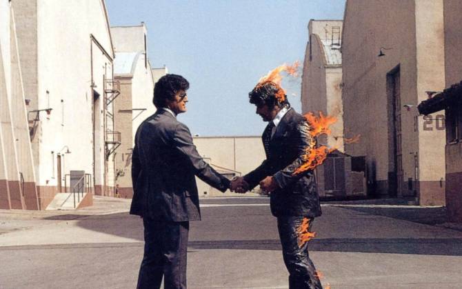 Two men shake hands as one bursts into flames for the cover art of Pink Floyd's Wish You Were Here.
