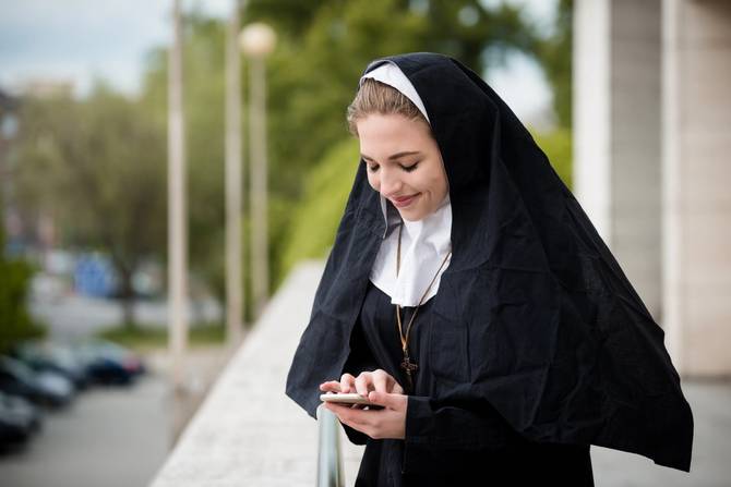 nun smiling and looking at phone