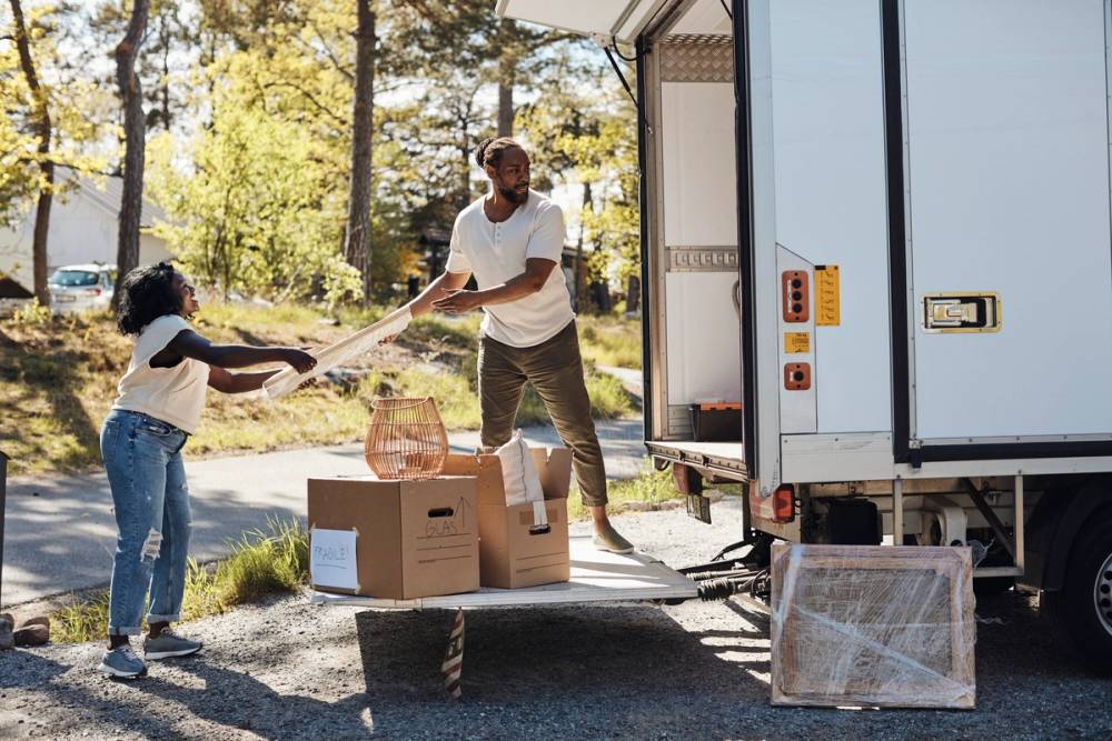 A couple moving boxes into a moving truck. 