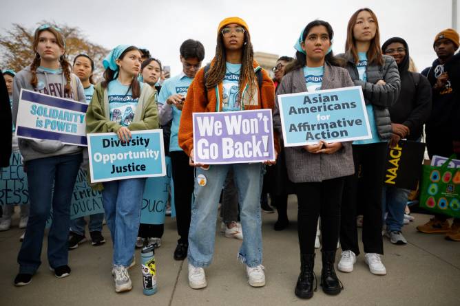 Image of several young girls all of different races, standing firmly, holding signs in support of diversity