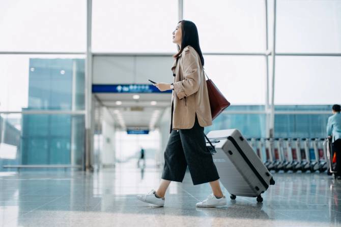 woman in airport walking with suitcase