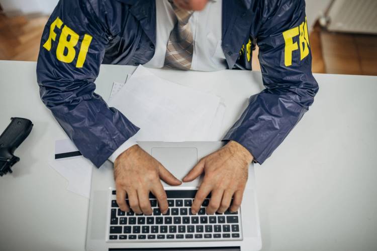 A senior FBI agent uses a laptop in the office.