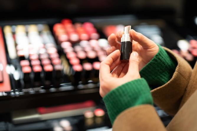 Woman looking at lipstick in beauty retailer