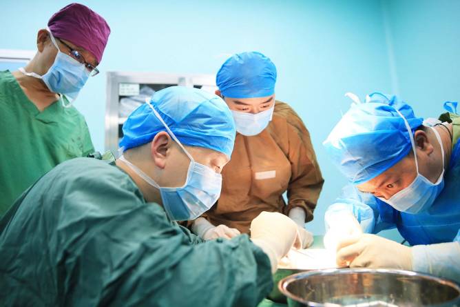 Masked surgeons performing a kidney transplant