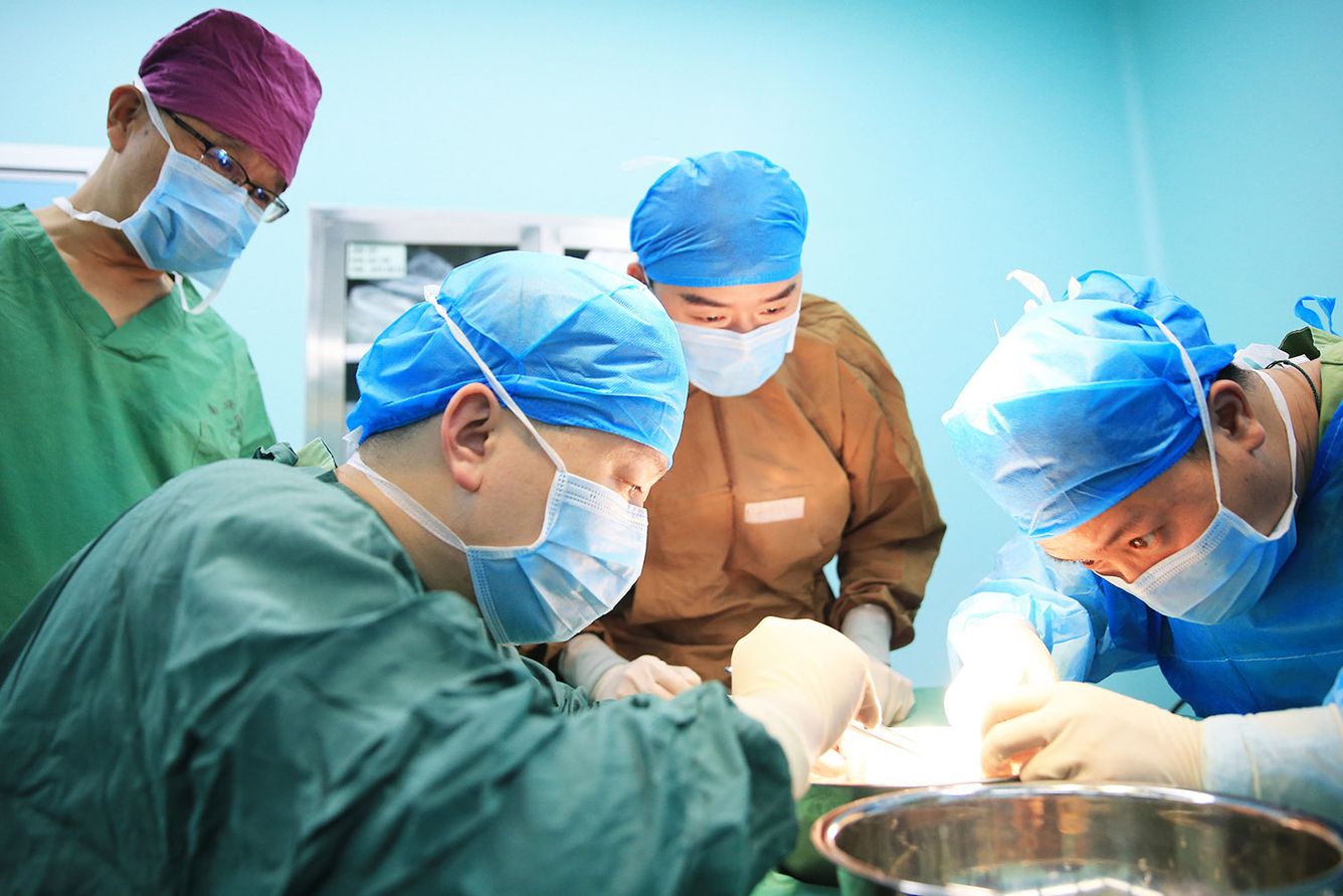 Masked surgeons performing a kidney transplant