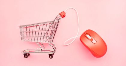 A shopping cart attached to a computer mouse on a pink background