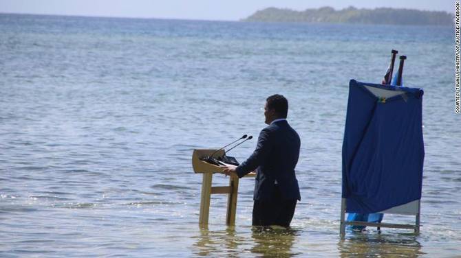 Tuvalu's foreign minister gives an address standing in water 
