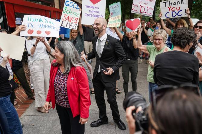 Former Centers for Disease Control (CDC) officials Deb Houry and Demetre Daskalakis smile while employees and supporters of the CDC line up outside the CDC global headquarters to honor the three leaders who resigned in the wake of U.S. President Donald Trump's firing of CDC director Susan Monarez
