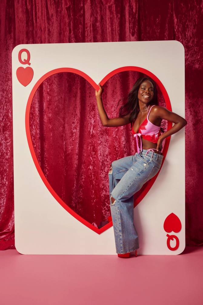 Lingerie model siting in a large queen of hearts card