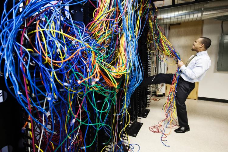 A computer tech yanks at tangled cables.