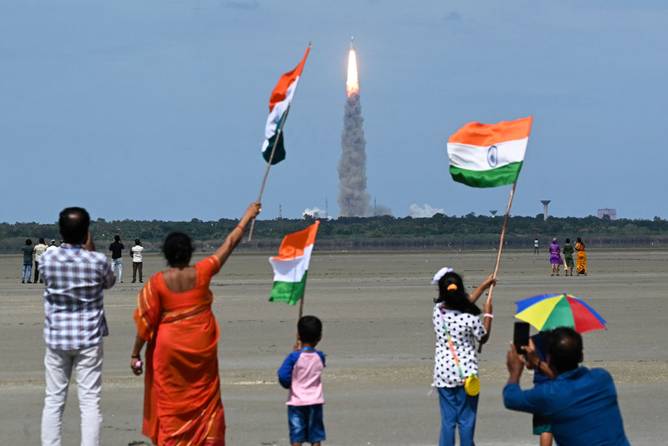 People wave Indian flags as an Indian Space Research Organisation (ISRO) rocket carrying the Chandrayaan-3 spacecraft