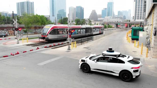 A Waymo vehicle stopped in front of a MetroRail track in Austin.