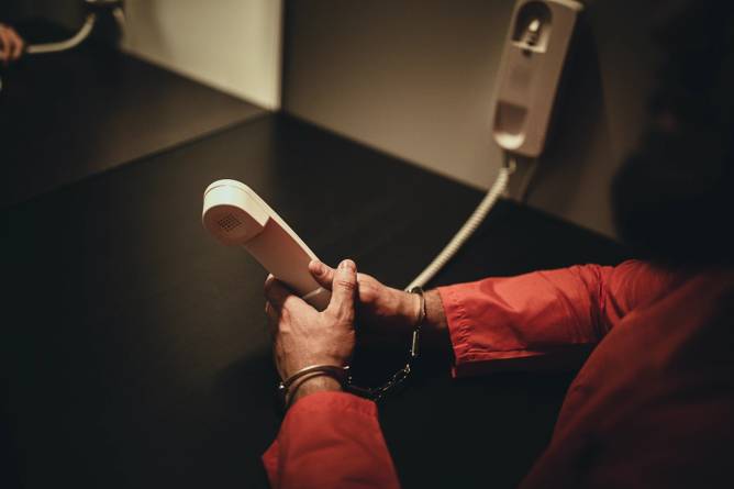 Male inmate holding phone 