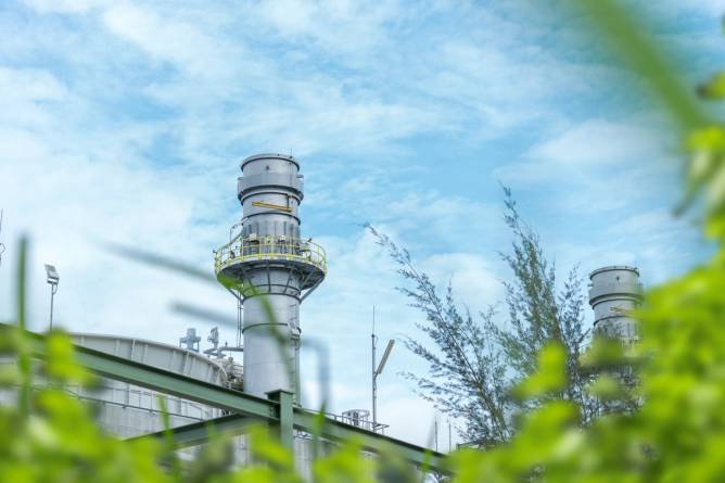 A gas separation plant with tree branches in the foreground.