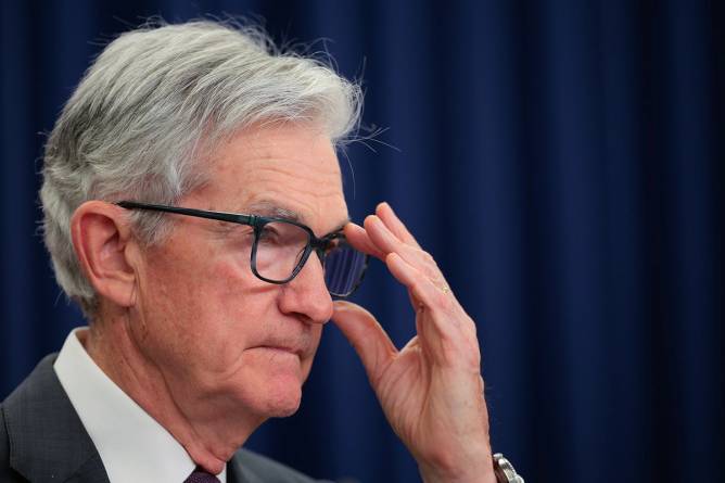 Jerome Powell adjusting his glasses.
