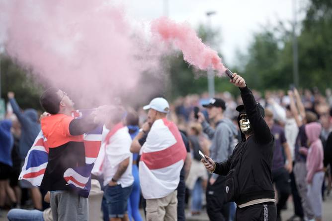 An anti-migration protester holds a flare during a riot outside of the Holiday Inn Express in Manvers,