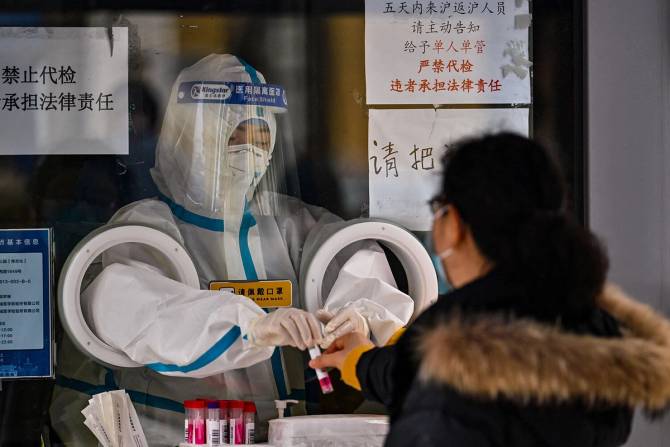 A health worker prepares to take a swab sample from a woman to test for the Covid-19 coronavirus in the Jing'an district in Shanghai