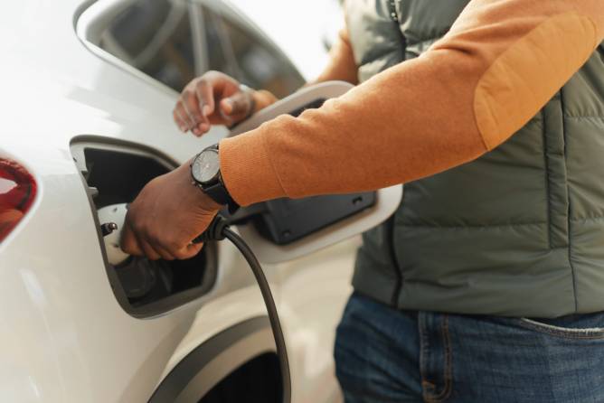 A man connects an EV to a charging cord.