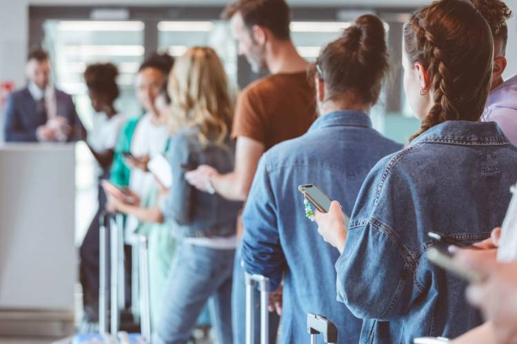 Passengers using phones waiting to board plane.