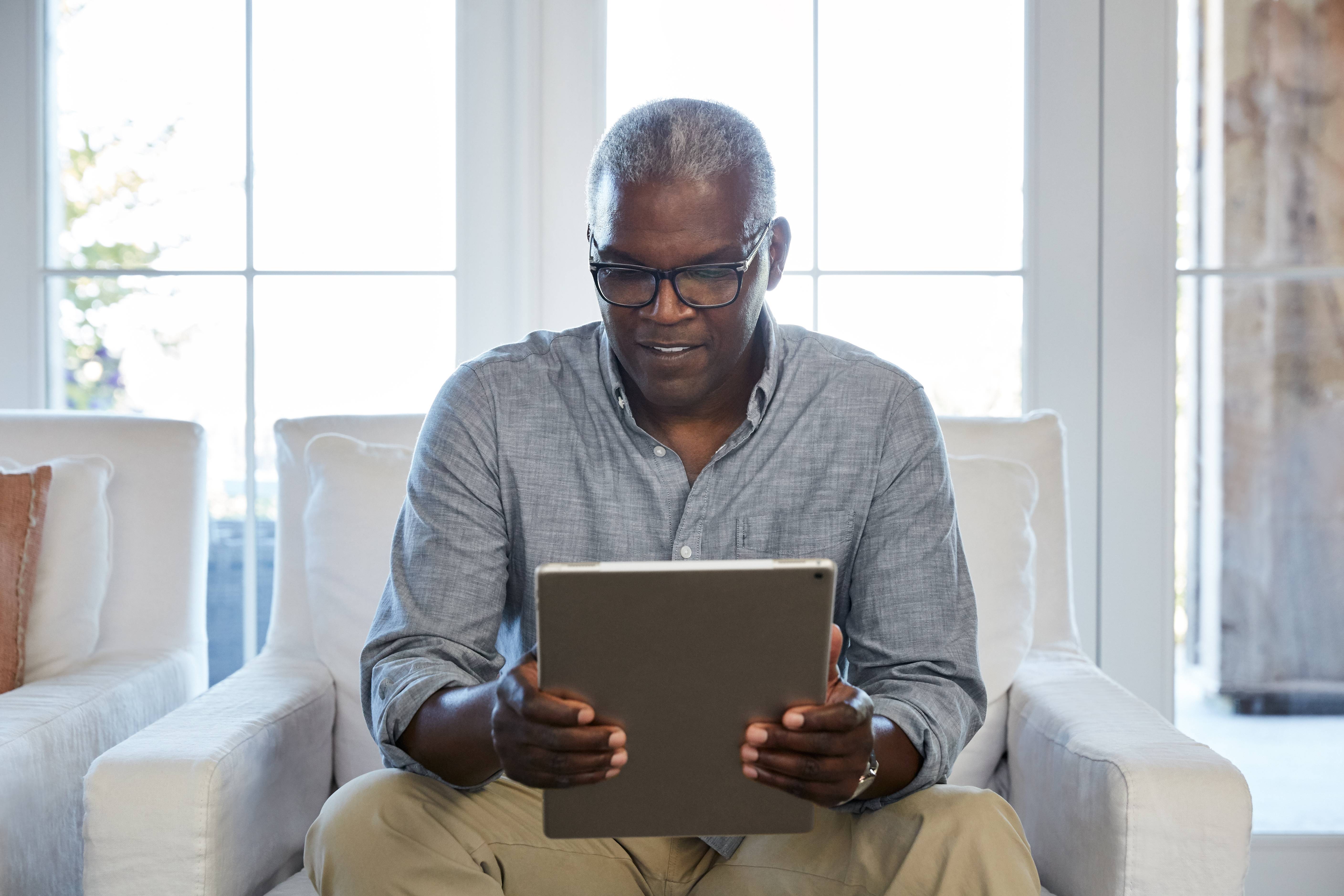 Man reading off a tablet sitting on a chair