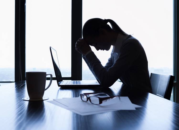 Unhappy women cradles head in hands in office