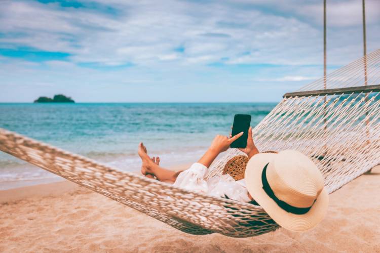 Woman looks at her phone on the beach