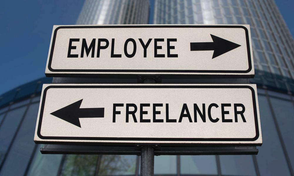 A pole with two street signs affixed to it. The top has "employee" written on it with a right-pointing arrow, the bottom states "freelancer" with a left-pointing arrow.