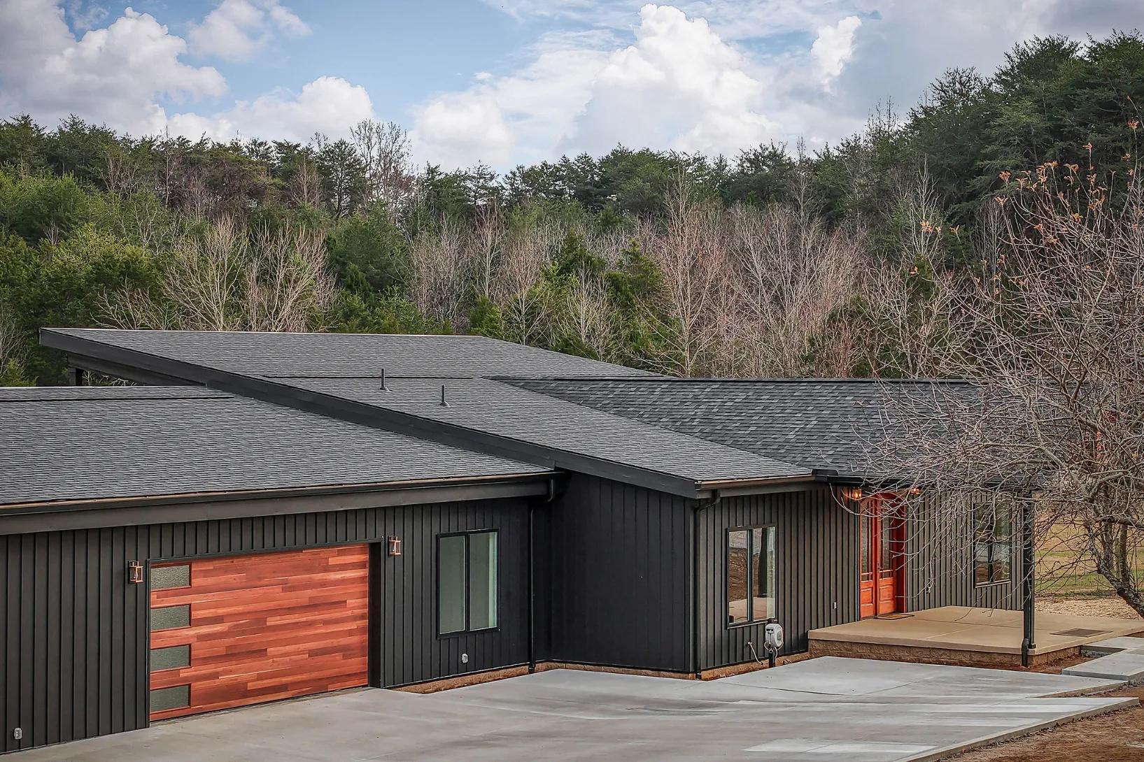 Outside drone view of beautifful black themed modern home with maple wood accents